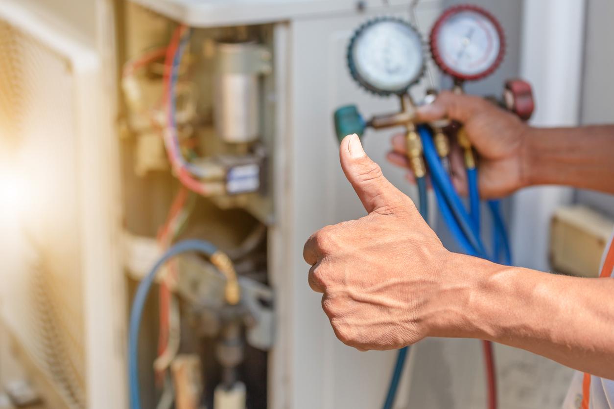 A technician giving a thumbs up sign as he provides maintenance service on a furnace.