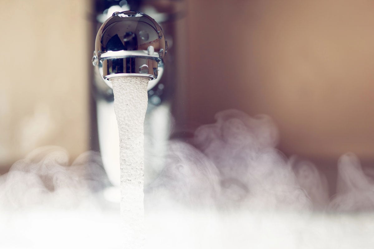 Hot water flowing from a modern faucet with steam rising, symbolizing energy-efficient water heating.