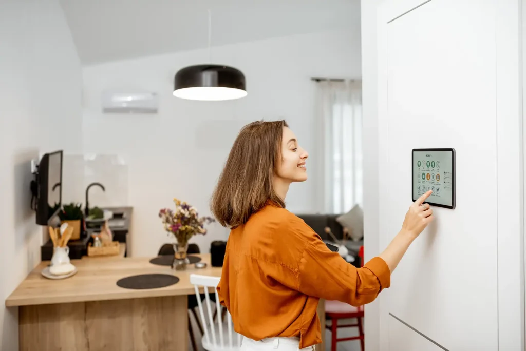 woman in orange controlling home automation via smart thermostat